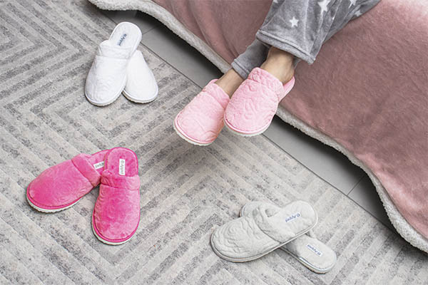 Mulher sentada na cama com uma pantufa lady appel home